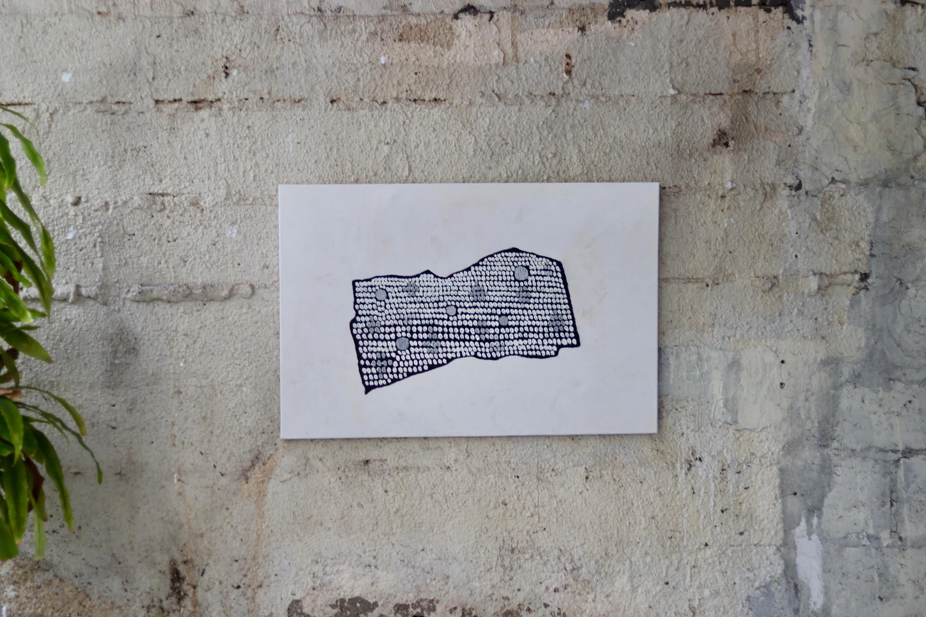 Ghorba artwork installed against a textured wall.